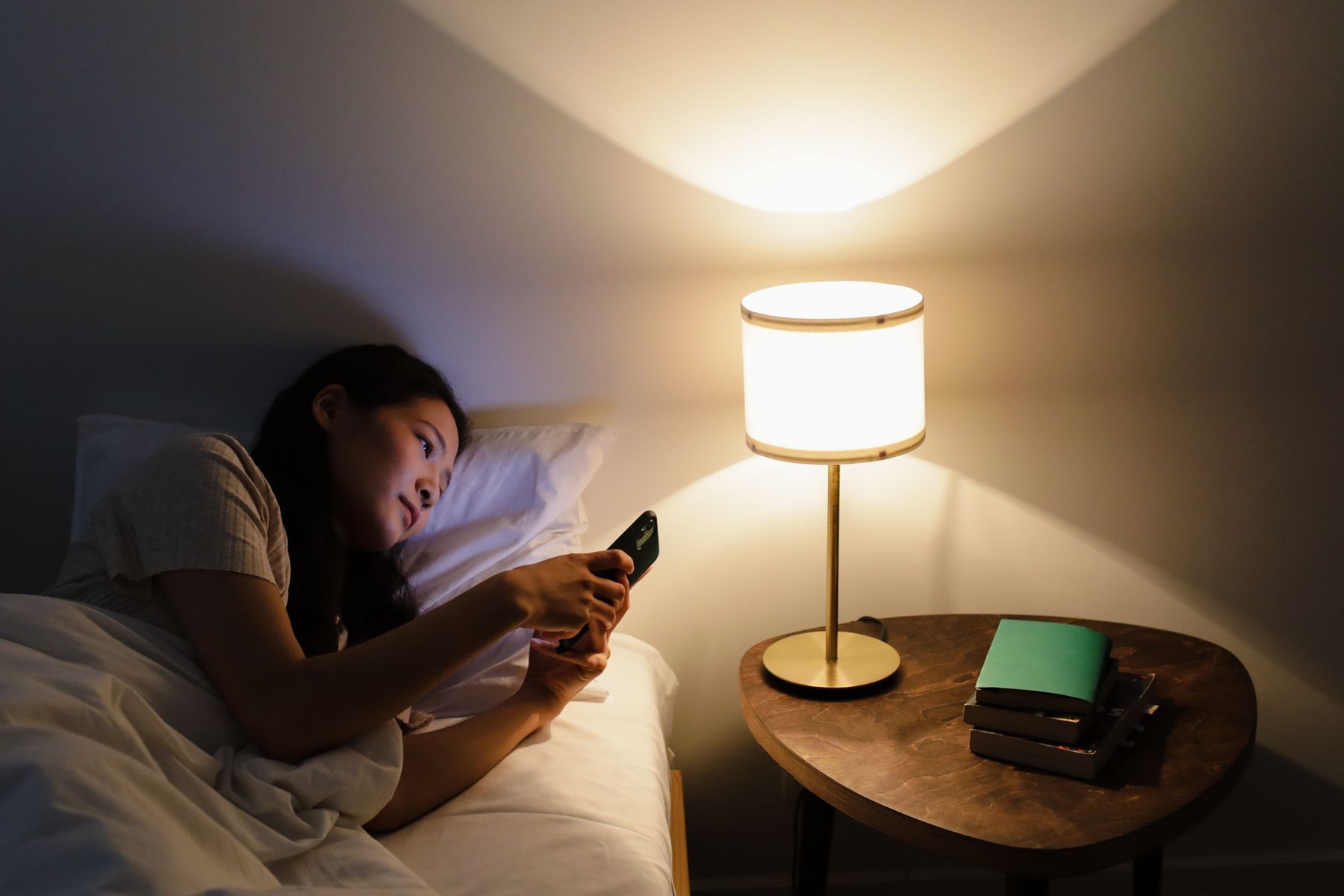 Seseorang memeriksa ponsel di tempat tidur pada malam hari
